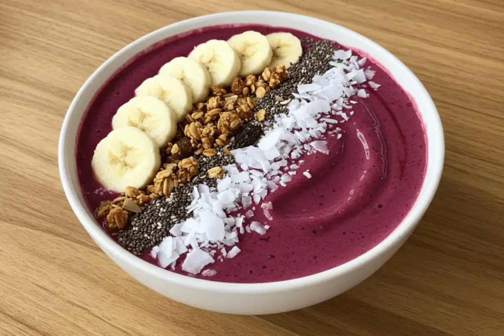 A smoothie bowl topped with banana slices, chia seeds, granola, and peanut butter, offering a delicious and nutritious breakfast.