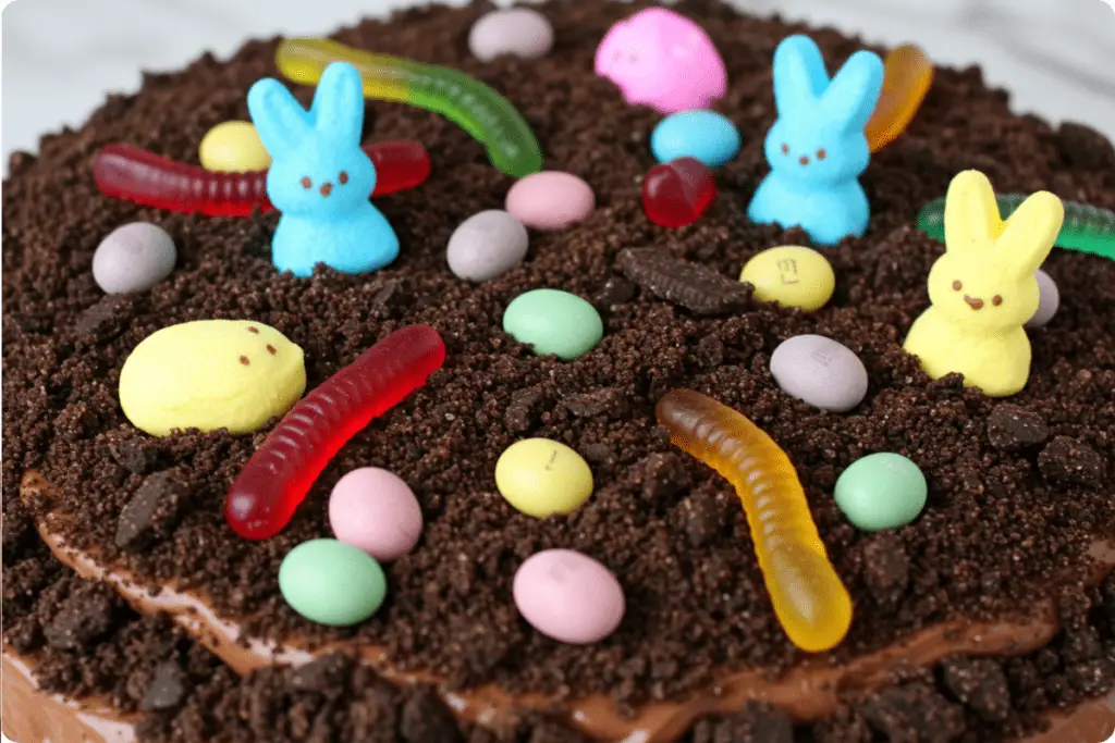 An Easter Dirt Cake decorated with candy eggs, chocolate bunnies, and marshmallow Peeps, resembling a spring garden with edible “dirt.”