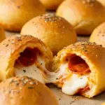 Golden, cheesy pizza bombs filled with pepperoni and mozzarella, brushed with garlic butter and sprinkled with parmesan, served with marinara sauce for dipping. Perfect for an easy party snack.