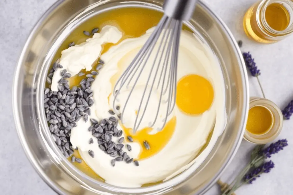 A creamy cheesecake filling being mixed with honey and lavender buds, ready to be poured over the crust for the cheesecake bars.