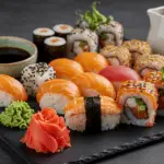 A beautifully arranged sushi platter with assorted rolls, pickled ginger, wasabi, and soy sauce, ready for serving.