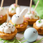 A bright and festive Easter appetizer platter with deviled eggs, pastel cheese cubes, puff pastry bites, and fresh veggies, garnished with herbs and edible flowers for a fresh spring look.