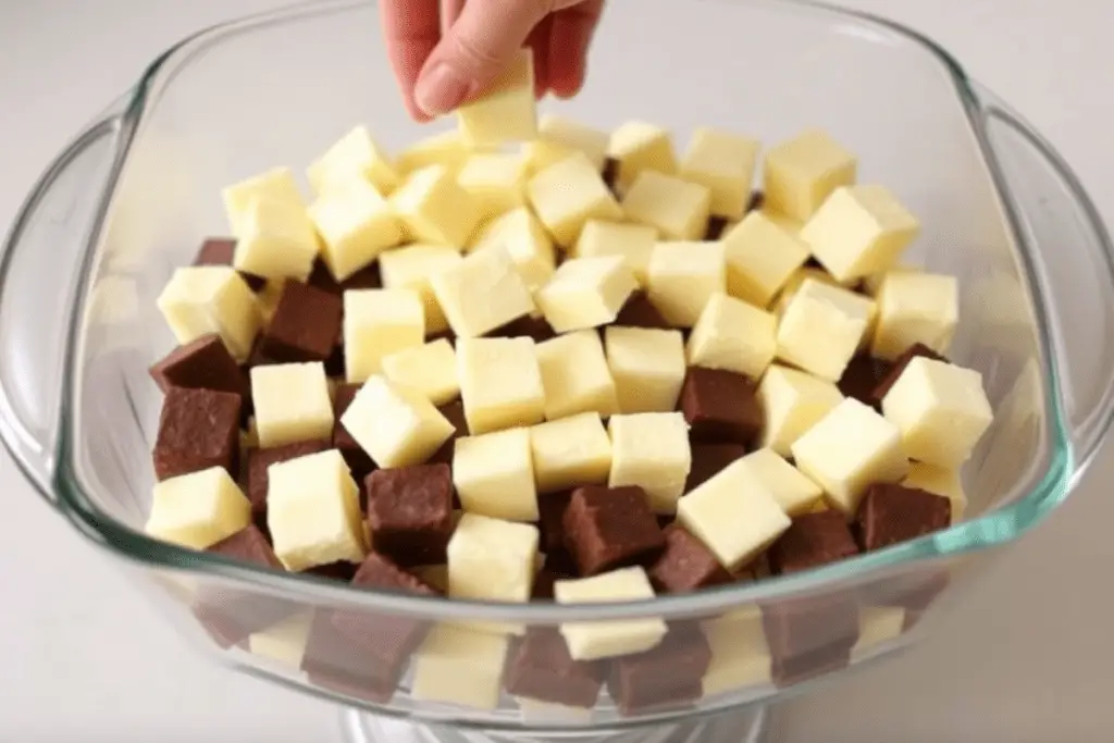 A glass trifle dish with cubed vanilla and chocolate cake, forming the first layer of a Hogwarts-themed dessert.