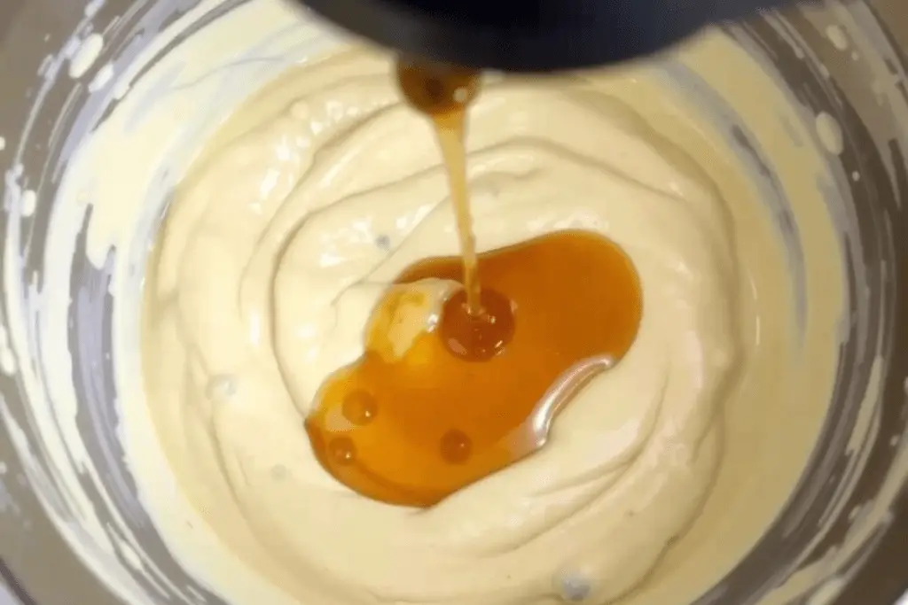 A bowl of pancake batter being whisked with maple syrup for a slightly sweet flavor, perfect for Mini McGriddle Bites.