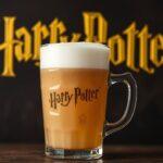 A glass mug of homemade Butterbeer topped with frothy butterscotch foam and drizzled with syrup, ready to serve.